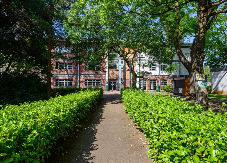 Loreto College's Ward Building at the end of a hedge lined path.