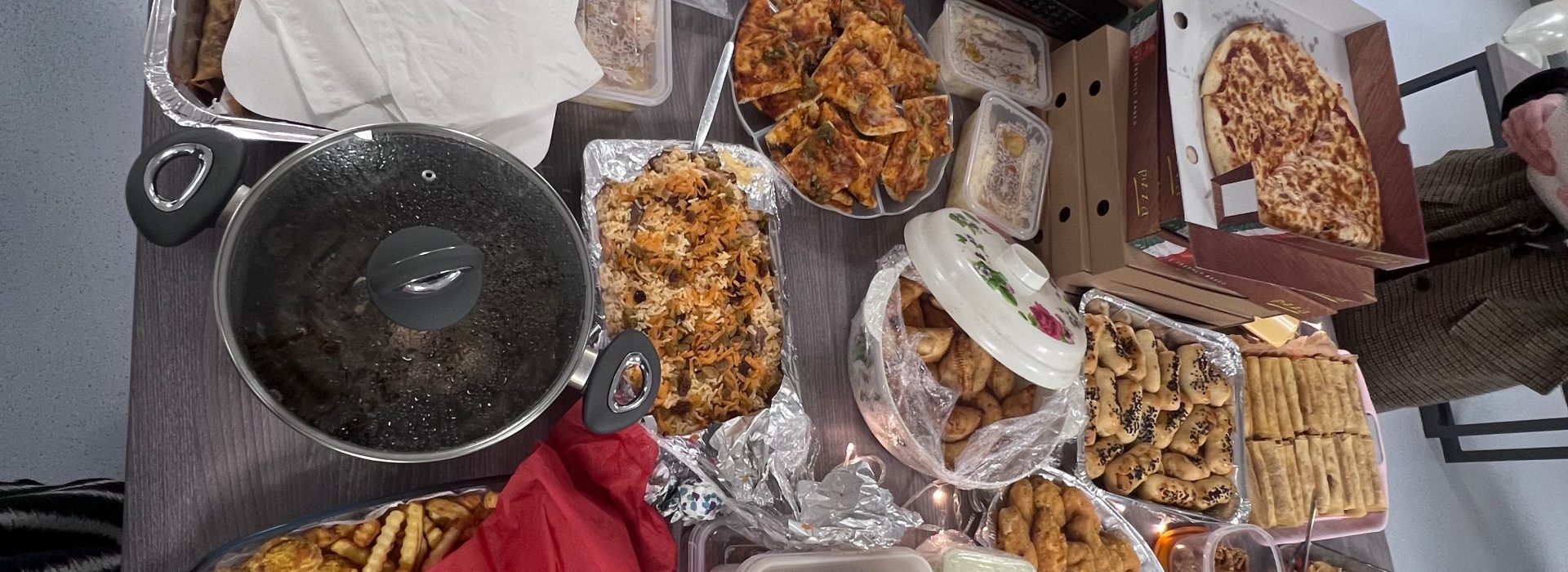 A variety of savoury food like rice, samosas and chicken all displayed on top of a large table.