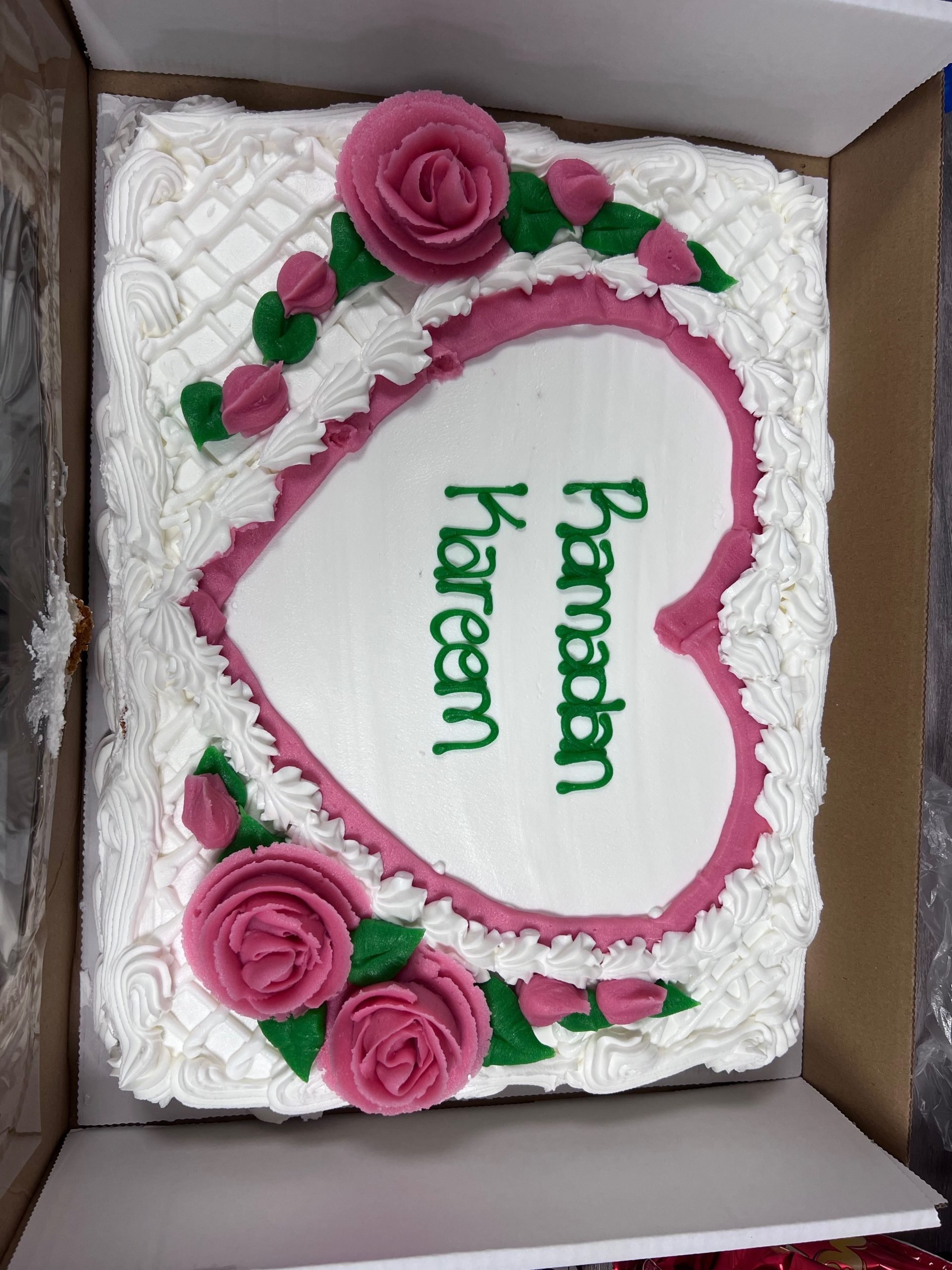 Beautiful cake decorated with pink roses and green leaves made with icing and Ramadan Kareem iced in green on the top.
