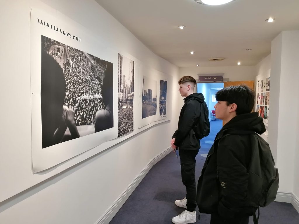 two young male students looking intently at photographs huge on the wall of an art gallery