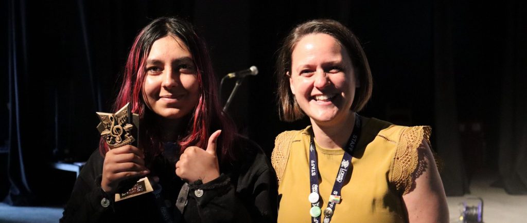 student with award gives thumbs up to teacher