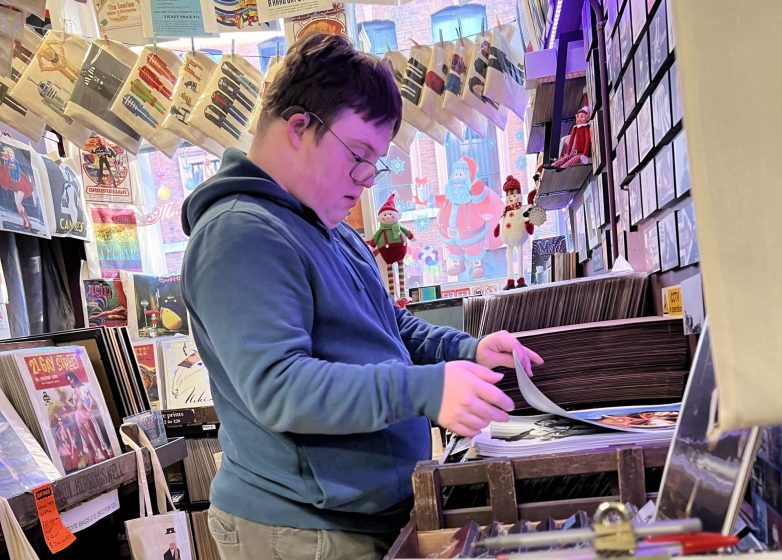 Student sorting out posters in a music shop.