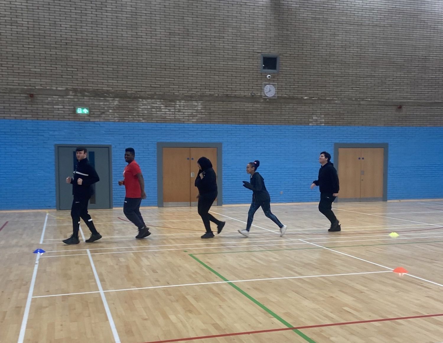 4 students and their teacher power walking in a gym.