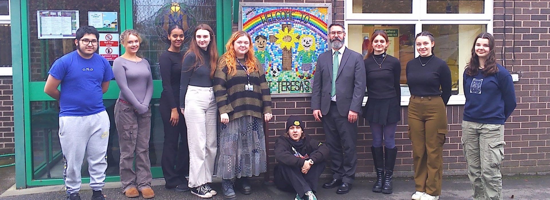 Students standing outside a primary school with the headteacher.