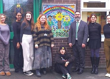 Students standing outside a primary school with the headteacher.