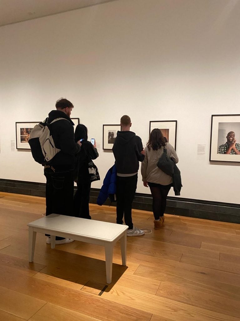 Four students inside National Portrait Gallery looking at framed. photographs on display.