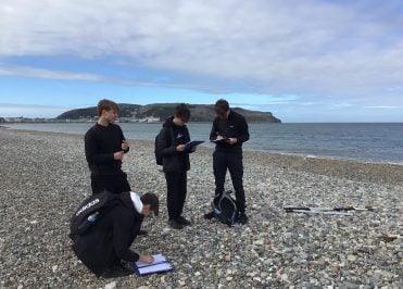 Small group of Loreto students on the pebbled beach in Llandudno.