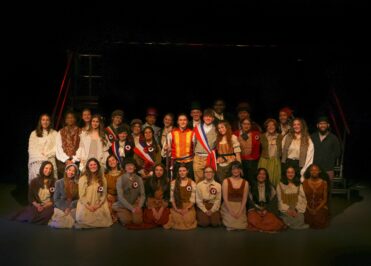students from teh production dressed in costumes from 19th century france in the production of Les Miserables