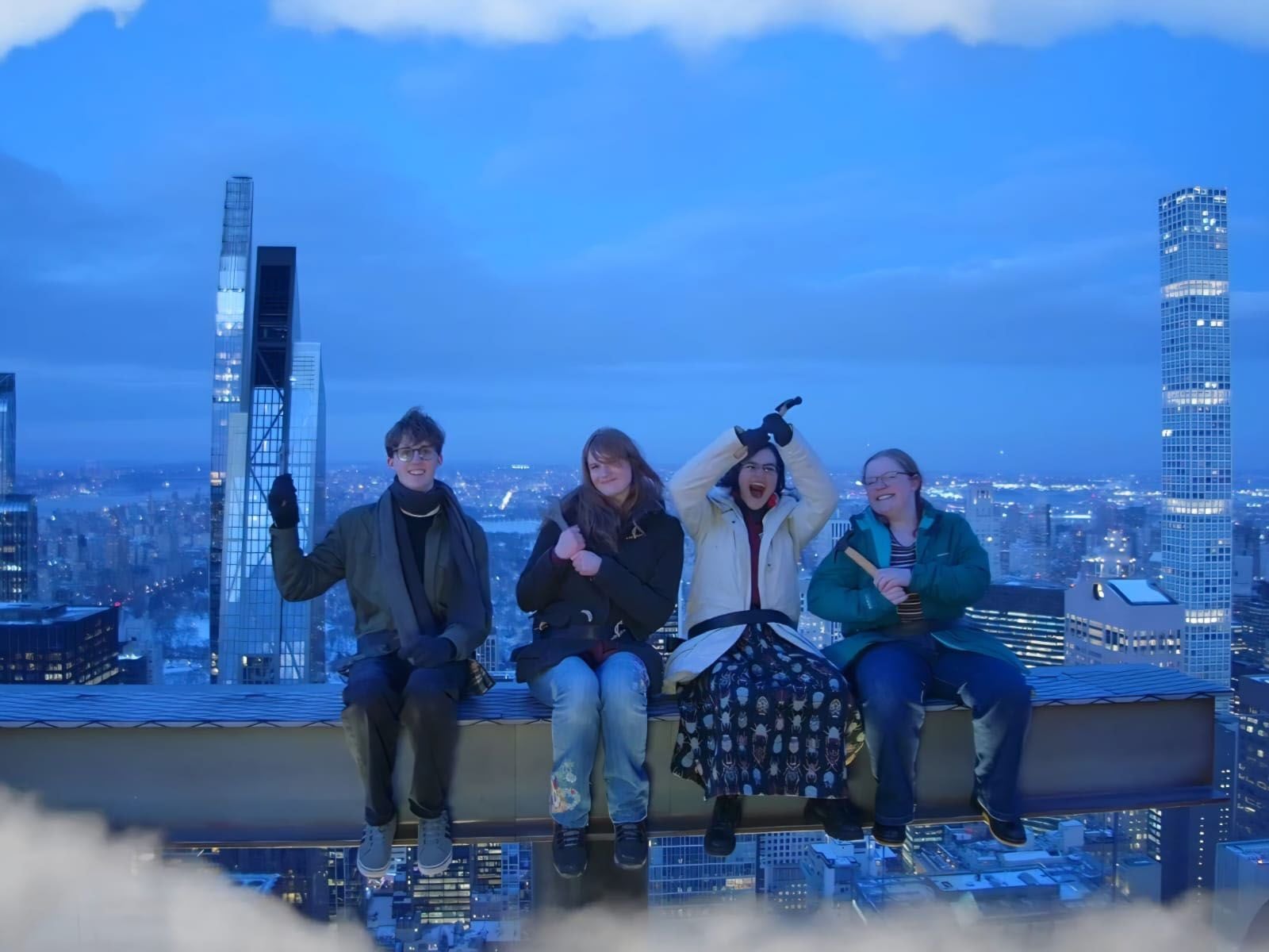 Four Loreto art students seated on the Beam Experience at the Top of the Rock, at the Rockefeller Center, overlooking the New York City skyline at dusk.”