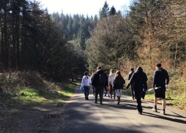 Geography students walking along a forest track in Macclesfield Forest during River Bollin fieldwork.