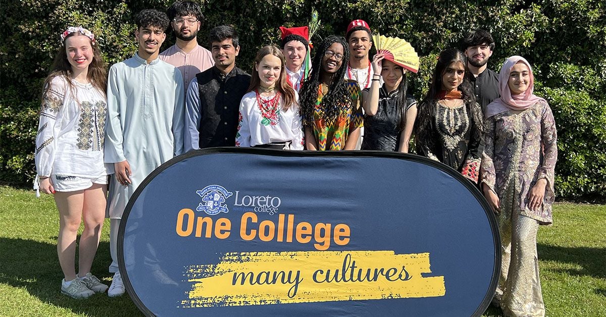 Students in traditional dress at Loreto College Manchester celebrating cultural diversity during Cultural Appreciation Day, with “One College many cultures” sign.