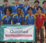 Loreto College students with medals holding a “Qualified AoC Sport National Championships” banner in a sports hall