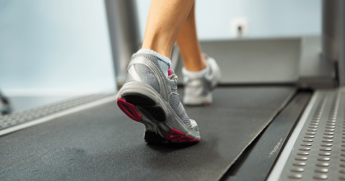 Close-up of a person's trainers walking on a treadmill in a modern indoor gym
