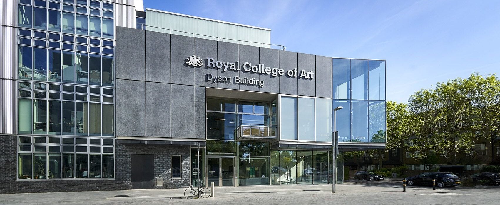 Exterior view of the Royal College of Art Dyson Building at the Battersea campus, featuring a modern glass-fronted entrance and contemporary architecture.