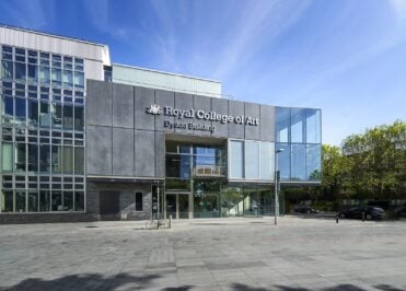 Exterior view of the Royal College of Art Dyson Building at the Battersea campus, featuring a modern glass-fronted entrance and contemporary architecture.